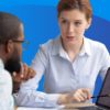 Two individuals engaged in candidate evaluation at a table with a laptop.