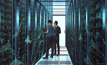 Two people standing in a server room discussing an ATS Data Migration.