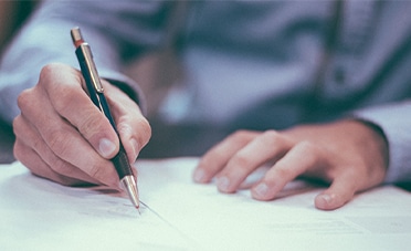 A person signing an offer letter with a pen.
