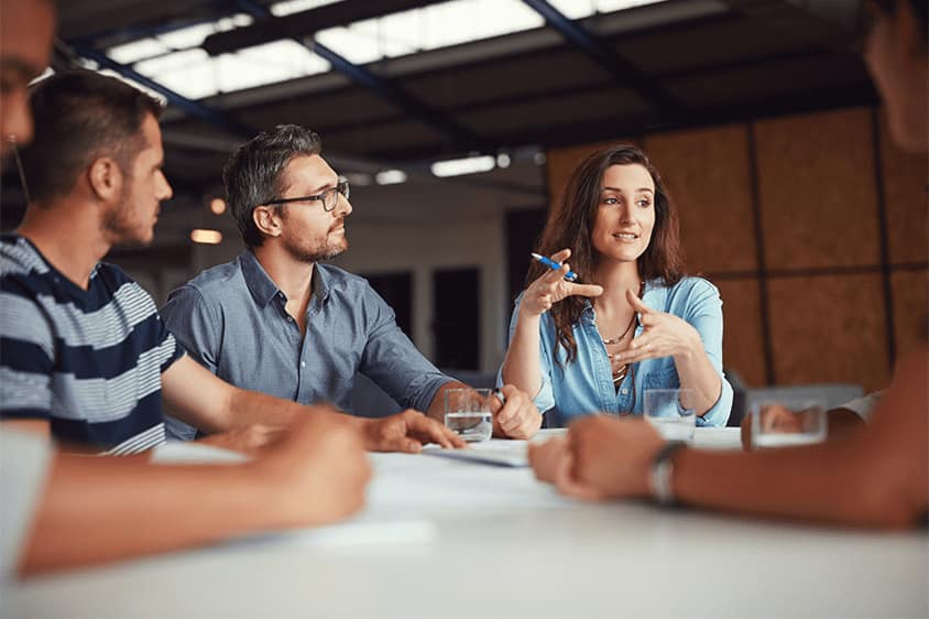 A group of people sitting around a table in a talent management meeting.