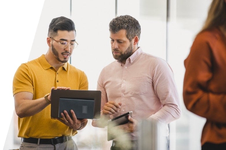 Two coworkers using a tablet in a workplace.