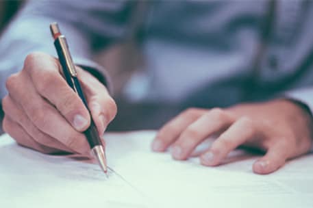 A man using a pen to sign an offer letter template.