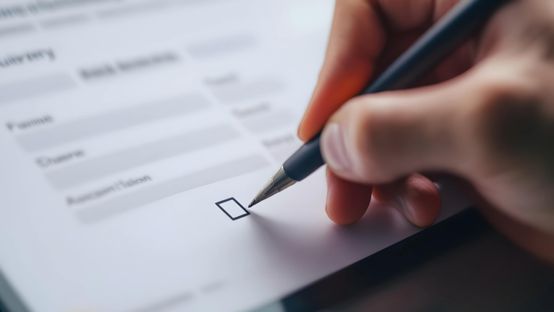 Hand holding a pen over an empty checkbox on an application form