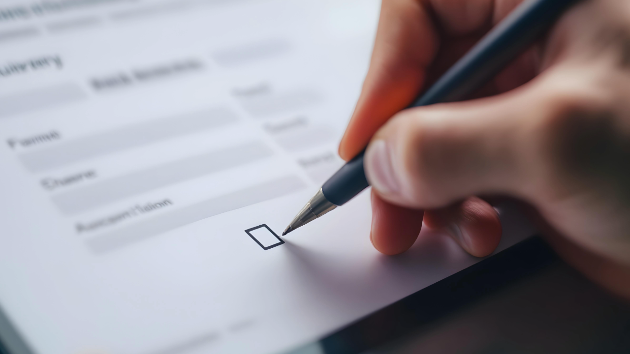 Hand holding a pen over an empty checkbox on an application form