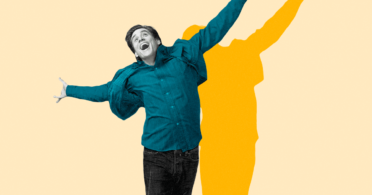 A man with his arms outstretched on a yellow background.